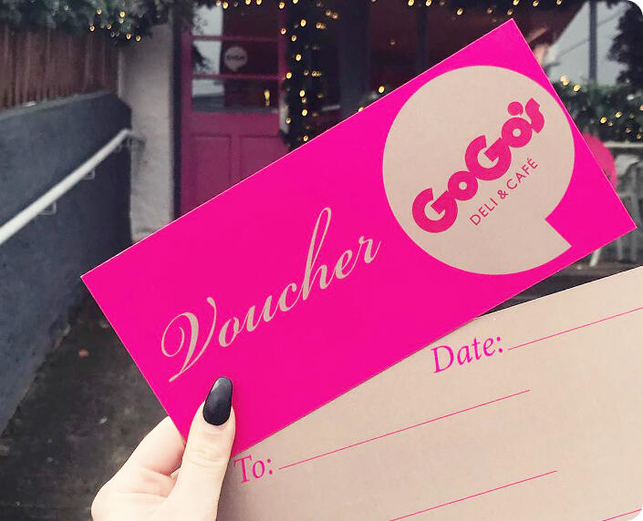A hand holding a pink GoGo's gift voucher